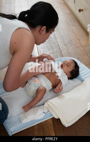 Baby Boy liegend auf seinem Rücken zu weinen, während seine Kleider in geändert Stockfoto