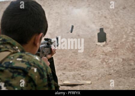 Eine syrische Demokratischen Kräfte Soldat feuert seine AK-47 Sturmgewehr auf ein Ziel während einer Live-Fire Training übung an einem Außenposten in der Nähe von Shaddadi, Syrien, 27. Mai 2018. Die Ausbildung ist so konzipiert, dass diese Soldaten für die Wiederaufnahme des Betriebs Zusammenfassung, den SDF vorzubereiten - LED-Offensive der letzten ISIS Hochburgen im Land zu löschen. Stockfoto