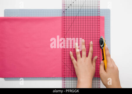 Frau schneiden mit Lineal und Rotary Cutter Stoff, close-up Stockfoto
