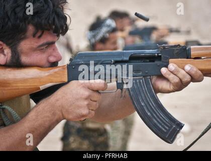 Eine syrische Demokratischen Kräfte Soldat feuert seine AK-47 Sturmgewehr auf ein Ziel während einer Live-Fire Training übung an einem Außenposten in der Nähe von Shaddadi, Syrien, 27. Mai 2018. Koalition Berater der Ausbildung diese Soldaten für die Wiederaufnahme des Betriebs Zusammenfassung, den SDF vorzubereiten-geführten militärischen Offensive der letzten ISIS Hochburgen im Land zu löschen. Stockfoto