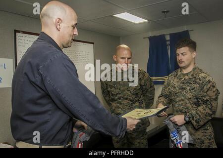 Atlantischer Ozean (26. Mai 2018) U.S. Navy Cmdr. Philip Knight, kommandierender Offizier der Harpers Ferry-Klasse dock Landung Schiff USS Oak Hill (LSD 51), präsentiert die Marine Im Spotlight Award und Silver Surfer t-shirt Marine Corps Sgt. Gavin Glon, ein Eingeborener von South Bend, Indiana und ein Tank Commander zum Tank Platoon, Fox, Bataillon Landung Team, 2.BATAILLON, 6 Marine Regiment, 26 Marine Expeditionary Unit, während der Fahrt in theAtlantic Ocean, 26. Mai 2018. Oak Hill, Home-in Virginia Beach, Virginia portiert, und der 26. MEU leiten naval Operations in den USA 6. Stockfoto