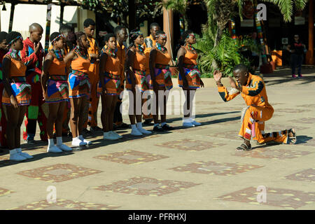 Young Zulu Mann in bunten kulturellen Kleid, vor einer Gruppe von traditionellen Straßenkünstler an uShaka, Durban, Südafrika Stockfoto