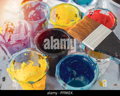 Acryl Farbe in Plastikbechern mit Pinsel und bunten artist Palette auf schmutzige Farben Hintergrund in der Kunst Studio. Stockfoto