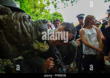 Ein U.S. Marine Corps Hornist, in einer Welt, die krieg ich Periode Uniform gekleidet, Getränke aus der Devil Dog Brunnen in der Stadt von Belleau, Frankreich, 27. Mai 2018. Die Bulldog Brunnen wird regelmäßig durch diejenigen, die sich auf die Belleau Wood Schlachtfeld, wo US-Marines den Spitznamen 'Devil Hund erwarb Reisen besucht." Stockfoto