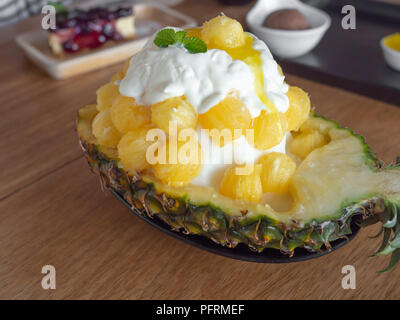 Eis Schnee Flocke. Süße Nachspeise koreanischen Stil Bingsu mit Ananas Geschmack Eis Kugel in einer Schüssel mit der Hälfte der frischen Ananas auf Holz- Tabl gemacht Stockfoto