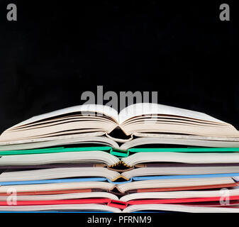 Stapel öffnen gebundene Bücher, auf schwarzem Hintergrund Stockfoto