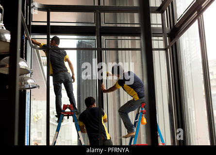 Nicht identifizierte Arbeitnehmer Anwendung gefärbten auf Glas Fenster Stockfoto