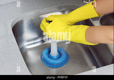 Frau tragen gelbe Abwasch Handschuhe mit Kolben Waschbecken aufzuheben, close-up Stockfoto