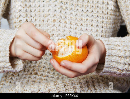Kind eine Orange schält Stockfoto