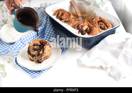 Cinnabon mit Schokolade. Hausgemachtes Gebäck in einer Auflaufform auf einem weißen Hintergrund. Freier Platz für Text. Ansicht von oben. Stockfoto