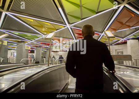 Oktober 2017, Russland - ein Mann auf der Rolltreppe in Moskauer Metro sieht bunte Decke von einer Station. Stockfoto