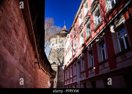 April 2016 - eine enge Passage zwischen der mittelalterlichen Stadtmauer und eine Stadt bauen führt zu einer beeindruckenden Runde Turm, Nürnberg, Deutschland Stockfoto