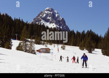 Garmisch-Partenkirchen, Deutschland - 7 April, 2018 - Skifahrer an einem Berghang; Wald und herrlichen schneebedeckten Alpen im Hintergrund Stockfoto