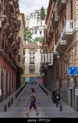 August 2017 - Eine Frau geht auf einer Straße in Granada, Spanien; historische Viertel Albaycin, anerkannt als UNESCO-Weltkulturerbe, ist auf der Spitze des Hügels Stockfoto