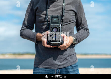 Person, die einen Retro twin lens reflex Kamera. Close Up, Taille. Stockfoto