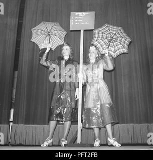 Frauen aus den 1940er Jahren in Regenmänteln. Zwei junge Frau in Regenmänteln aus Kunststoff zeigt ihnen Regenschirme. Schweden 1943 Ref. E47-5 Stockfoto