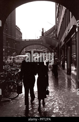 Verregnete Straße in den 1950er Jahren. Ein paar Fuß unter einem Sonnenschirm entlang einer Straße einen regnerischen Tag. Kungsgatan Stockholm 1953. Foto Kristoffersson ref 1 Stockfoto