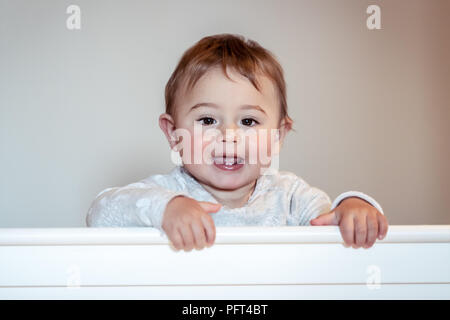 Porträt von einem niedlichen kleinen Jungen, die in der Krippe in Kinderzimmer, ziemlich adorable Baby tragen Schlafanzüge, glücklichen gesunden Kindheit Stockfoto