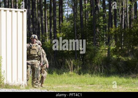 Staff Sgt. Ethan Abschaltdruck (links), einen Teamleiter mit 705Th Ordnance Company, 79th Ordnance Battalion, 71st Ordnance Gruppe (EOD), und sein Team Mitglied, SPC. Kooper Fordyce (rechts), bestimmen, dass der Bereich hinter einem großen Metall Storage Container ist ein sicherer Abstand von dem zu untersuchen und einer simulierten Sprengkörper zerstören, während ein Befehl Übung, Mai 21-24 in Fort Polk, Louisiana die Ausbildung, durch die 79. Ord gehostet werden. Bn., dient als eine wichtige Bewertung der 705th Ord. Amazon.de aktuelle Bereitstellung Fähigkeiten und Bereitschaft. Stockfoto