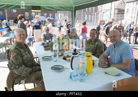 Us-Armee Sgt. Maj. Samuel Farley (rechts) und Maj. Emily Lynds (links), sowohl für die Resolute Schloss 18 zugeordnet, 218 Manöver Verbesserung Brigade, South Carolina Army National Guard, haben Dessert mit Kornel Filipowicz, der Vizepräsident von Boleslawiec, Polen, während der boleslawiec Grundschule Nr. 4 Festival in Boleslawiec, Polen, 26. Mai 2018. Resolute Schloss Soldaten wurden besondere Gäste des Festivals und in Sportveranstaltungen und Töpferei, Malerei mit der Grundschule Kinder teilgenommen. Stockfoto