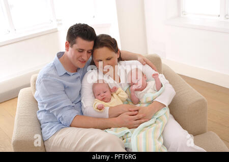 Mann und Frau sitzt mit zwei Jungen (3 Monate) Stockfoto