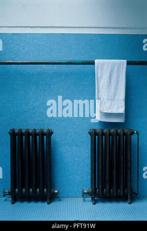 Weißes Handtuch trocknen auf der Schiene über zwei in die Umkleidekabine zwei altmodische Heizkörper Stockfoto