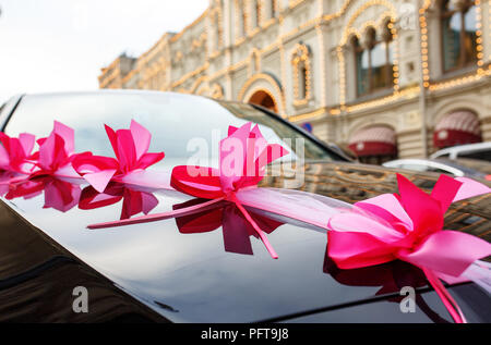 Schwarzes Auto mit einer rosa Schleife auf der Haube dekoriert Stockfoto