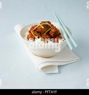 Huhn von General Tso serviert auf Bett aus Reis, Essstäbchen Stockfoto