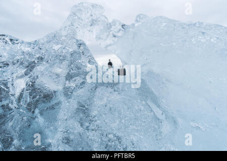 Auf der Suche durch die Bohrung in einem Eisberg gibt einen einzigartigen Blick auf Touristen auf Diamond Beach in Island. Stockfoto