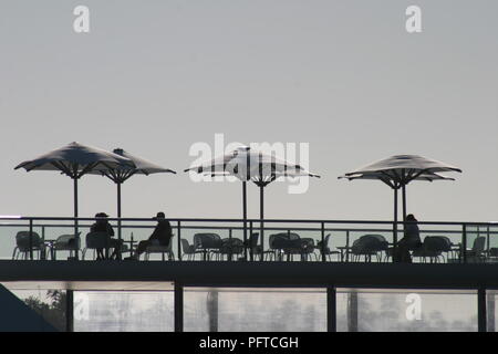 Menschen entspannen unter Sonnenschirmen am Hamilton Island Yacht Club Sonnenuntergang zu beobachten. Stockfoto