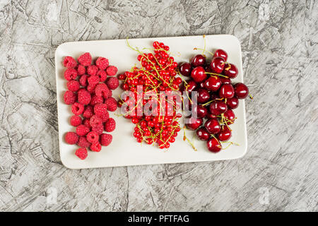 Gemischt viele verschiedene bunte Früchte der Saison, Himbeeren, Kirschen, Aprikosen, auf Platte, Ansicht von oben, kopieren Raum Stockfoto