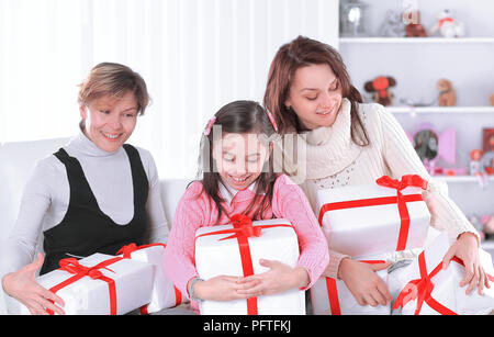 Großmutter, Mutter und Tochter mit geschenkboxen Sitzen auf der Couch. Urlaub Konzept Stockfoto