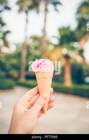 Woman's Hand Obst Eis in der Waffel Kegel gegen die Palmen. Stockfoto