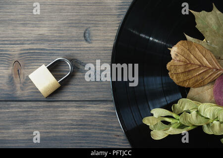 Messing Vorhängeschloss neben Vintage vinyl platten auf rustikalen Holz Hintergrund Zugriff auf Audiodateien Konzept mit kostenlose Kopie Raum Stockfoto