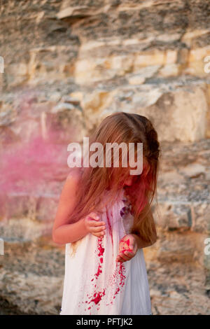 Ein kleines Mädchen mit Palmen das Blasen auf den Lack Holi rosa. Großer Moment. Stockfoto