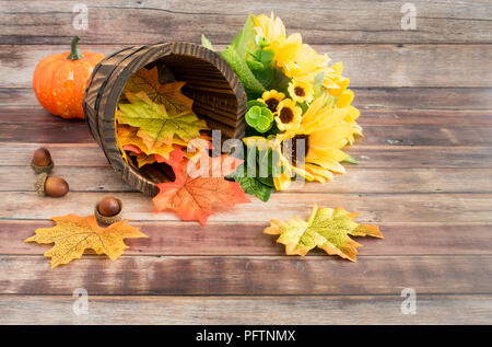 Sonnenblume Strauß, Kürbis, Eicheln und einem rustikalen Holzmöbeln Blumentopf mit bunten Blätter im Herbst auf braunem Holz gefüllt. Stockfoto