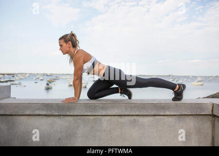 Junge Erwachsene Frau in Fitness Kleidung Ausübung auf Stein Wand Stockfoto