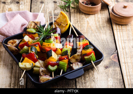 Gegrillte bunte Gemüse Spieße auf Gusseisen Skillet. Vegan Sommer Mahlzeit auf rustikalen Holztisch Stockfoto