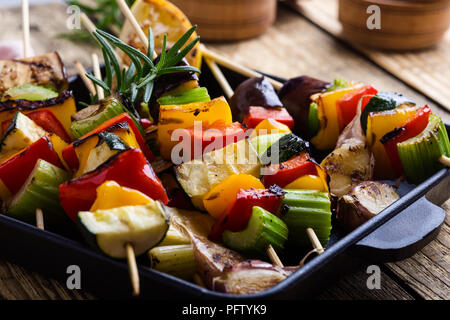 Gegrillte bunte Gemüse Spieße auf Gusseisen Skillet. Vegan Sommer Mahlzeit auf rustikalen Holztisch Stockfoto