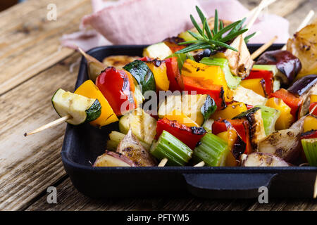 Gegrillte bunte Gemüse Spieße auf Gusseisen Skillet. Vegan Sommer Mahlzeit auf rustikalen Holztisch Stockfoto