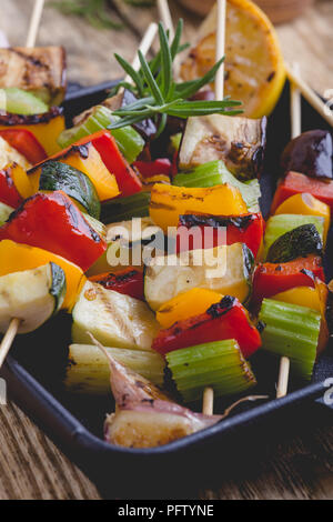 Gegrillte bunte Gemüse Spieße auf Gusseisen Skillet. Vegan Sommer Mahlzeit auf rustikalen Holztisch Stockfoto