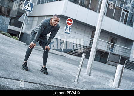 Urbane Sportarten. Junger Mann tut aufwärmen, bevor Sie in der Stadt, die auf einem Morgen Stockfoto