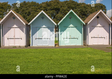 Reihe von bunten Badekabinen auf grün hinter Meer in Southsea in Portsmouth, Hampshire, England Stockfoto