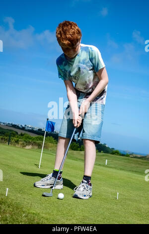 Junge Teenager üben, einen Golfball auf einem grünen. Cornwall Polzeath. Stockfoto