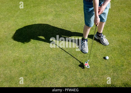 Beine von einem jungen Teenager Vorbereitung einer Golfkugel zu setzen. Cornwall Polzeath Stockfoto