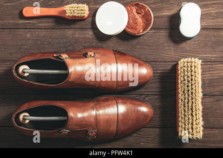 Schuhe aus Leder mit Zubehör für die Reinigung auf einem Holzbrett angeordnet Stockfoto