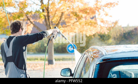Arbeitnehmer Reinigung Auto mit hohem Druck Wasser Düse Stockfoto