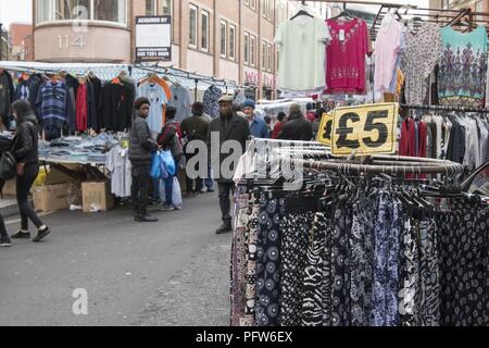 Käufer entfernt und inmitten von Racks mit Kleidung auf der Straße an der Petticoat Lane Market, im East End, in London, England, 29. Oktober 2017 Suchen. () Stockfoto