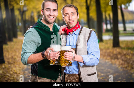 Männer in bayrischer Tracht klirren Gläser mit Bier Stockfoto