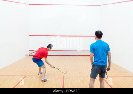 Ansicht der Rückseite zwei konkurrierende junge Männer spielen Squash Spiel Stockfoto